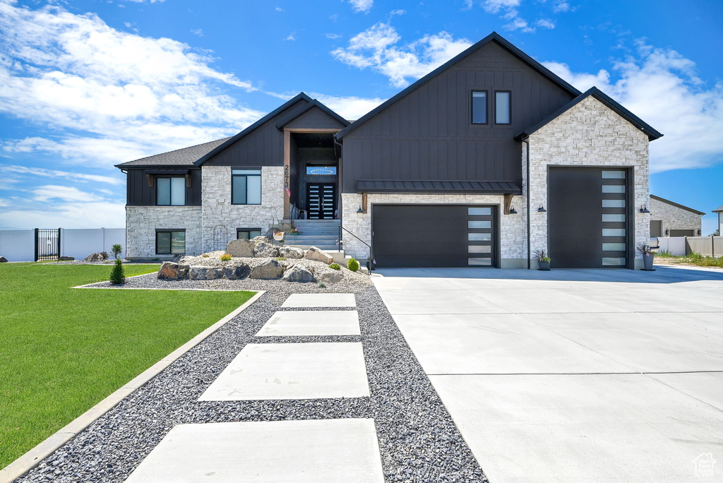 Modern home with board and batten siding, concrete driveway, stone siding, and a garage