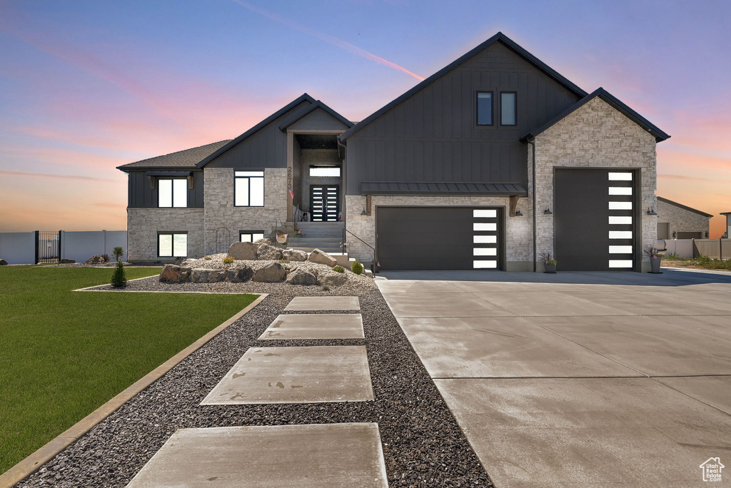 View of front of property featuring board and batten siding, concrete driveway, a standing seam roof, and an attached garage