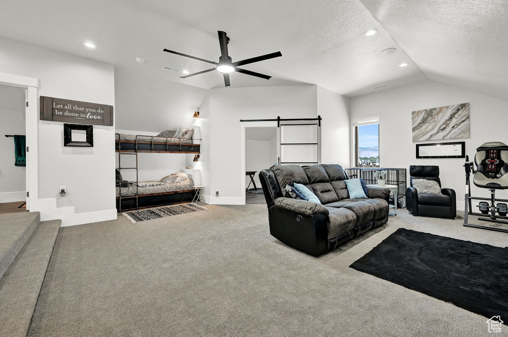 Carpeted living area with a barn door, a ceiling fan, lofted ceiling, recessed lighting, and a textured ceiling