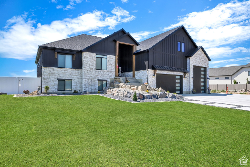 View of front of home with stone siding, driveway, board and batten siding, roof with shingles, and a standing seam roof