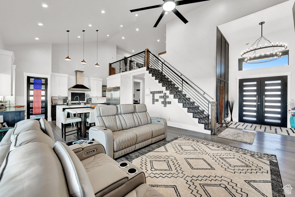Living room with high vaulted ceiling, recessed lighting, a chandelier, a ceiling fan, and wood finished floors