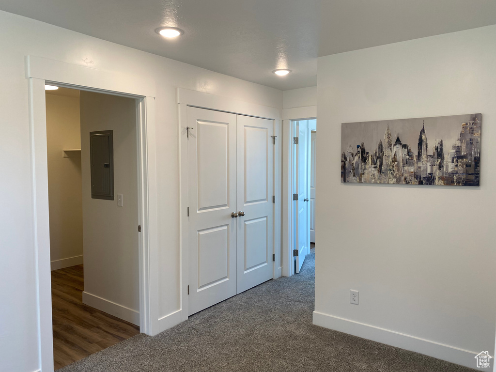 Hall featuring electric panel and dark carpet