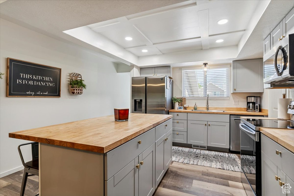Kitchen with wooden counters, stainless steel appliances, gray cabinets, light wood finished floors, and recessed lighting