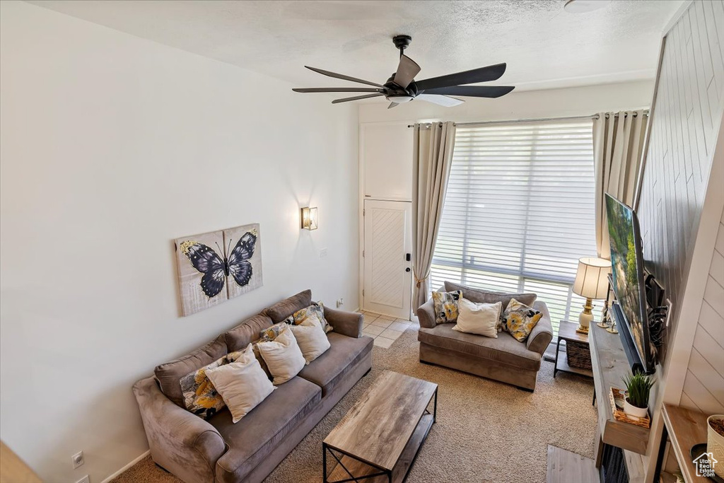 Living room featuring a ceiling fan, plenty of natural light, and light colored carpet