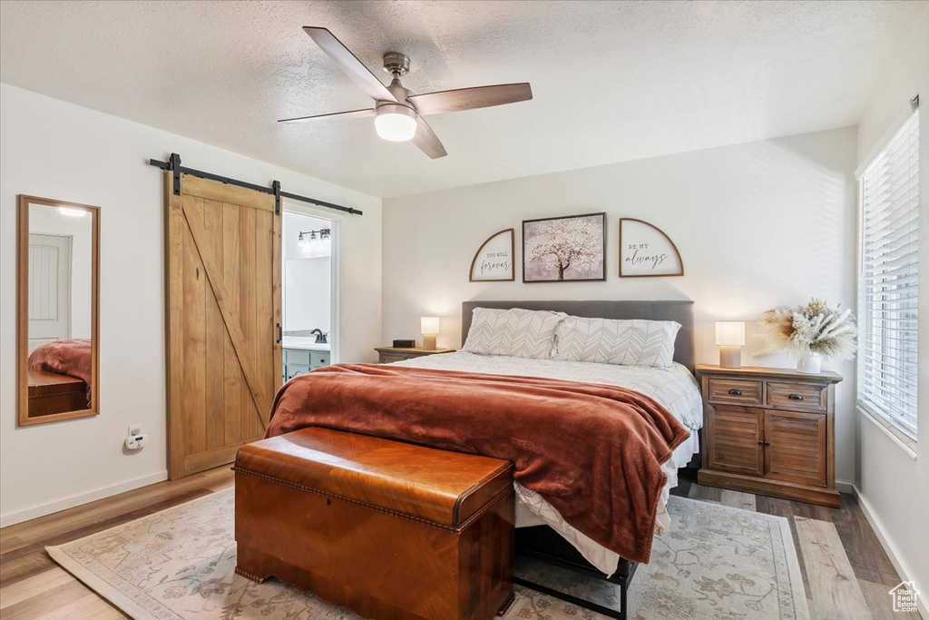 Bedroom with a barn door, wood finished floors, and multiple windows