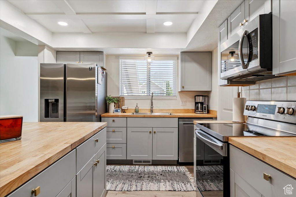 Kitchen with wooden counters, appliances with stainless steel finishes, gray cabinetry, and recessed lighting