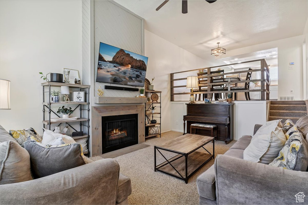 Living area featuring a ceiling fan, a fireplace, and carpet flooring