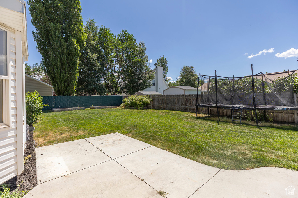 Fenced backyard with a trampoline and a patio area