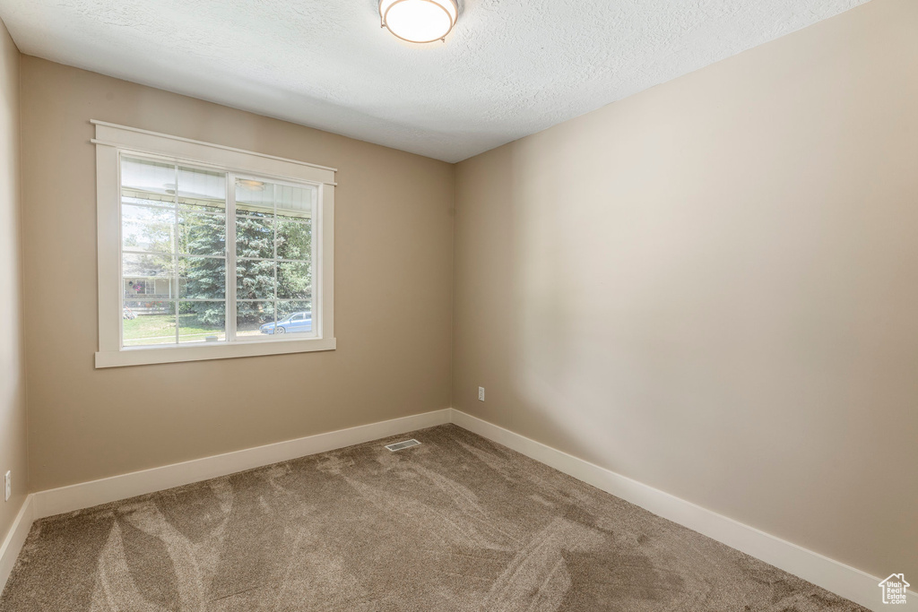 Carpeted empty room featuring baseboards and a textured ceiling
