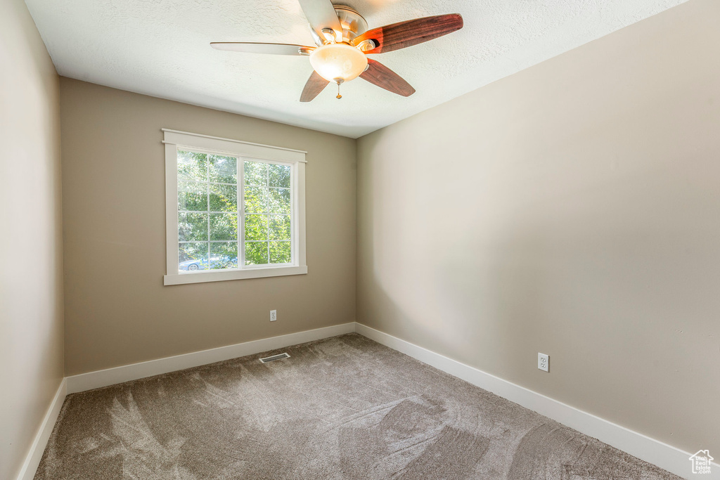 Spare room featuring ceiling fan, carpet floors, and a textured ceiling