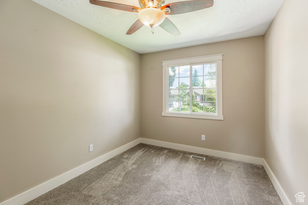 Spare room featuring carpet floors, ceiling fan, and a textured ceiling