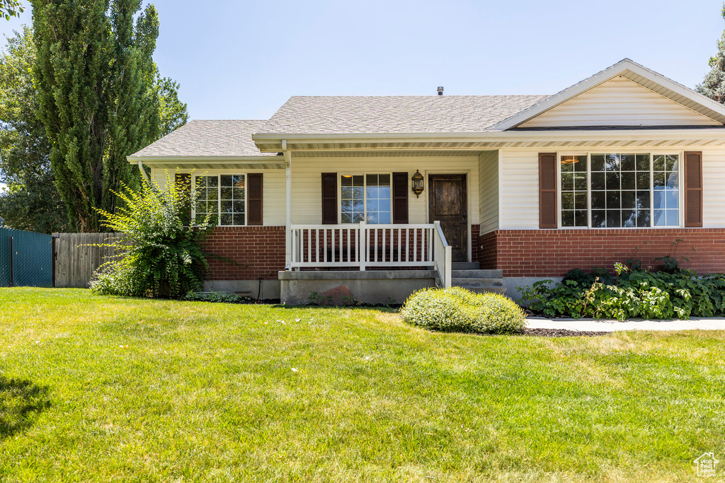 View of front of property with brick siding, a porch, and roof with shingles