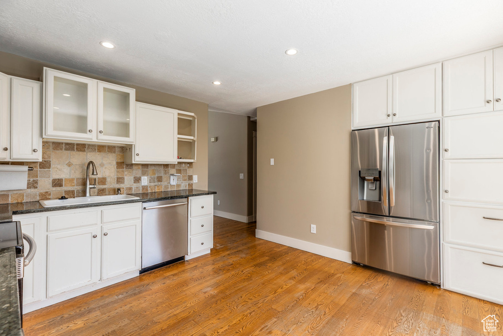Kitchen with appliances with stainless steel finishes, recessed lighting, white cabinetry, and light wood-style floors