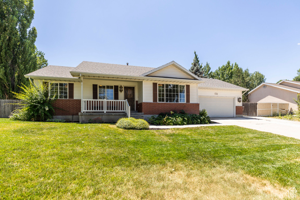 Ranch-style house with a porch, brick siding, concrete driveway, and a garage