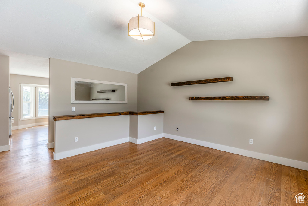 Unfurnished living room featuring wood finished floors and vaulted ceiling