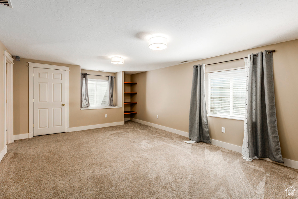 Unfurnished bedroom featuring light carpet and baseboards