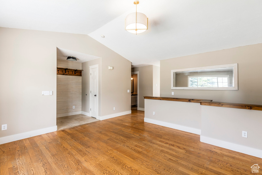 Unfurnished living room featuring light wood-style flooring and vaulted ceiling