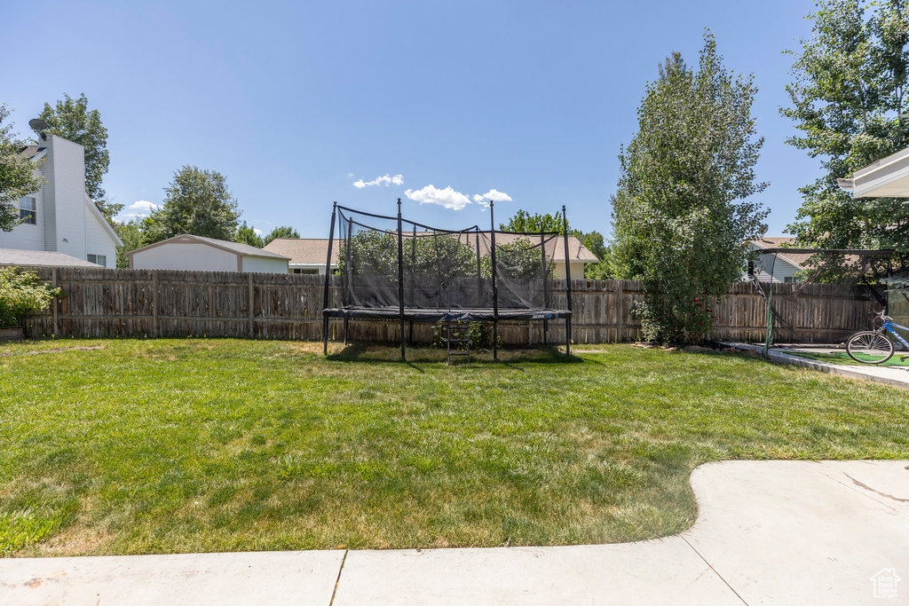 Fenced backyard featuring a trampoline