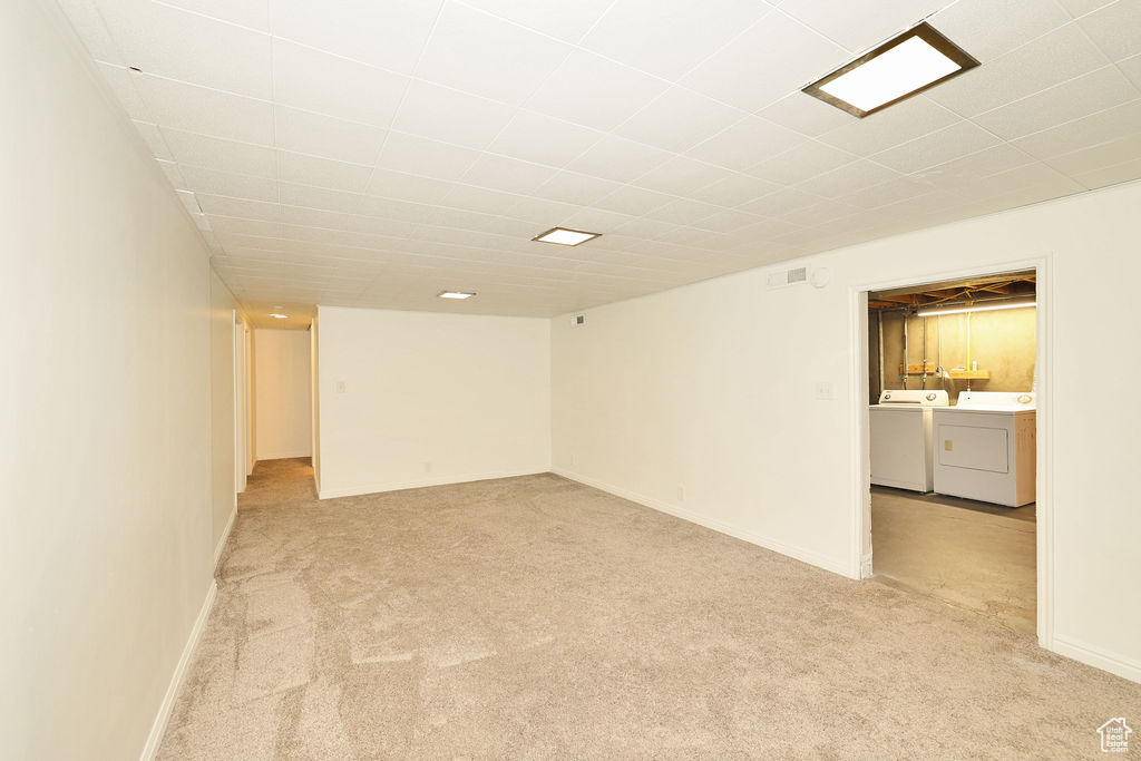 Empty room with washer and clothes dryer and light colored carpet