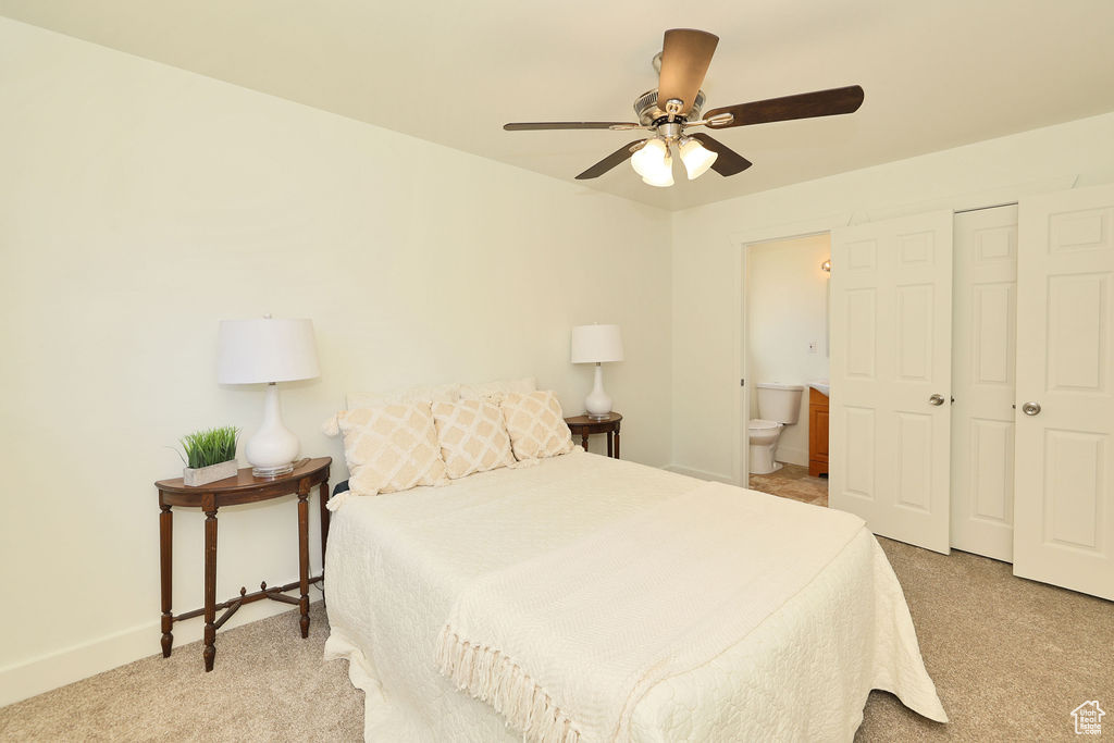 Carpeted bedroom with ensuite bathroom and ceiling fan