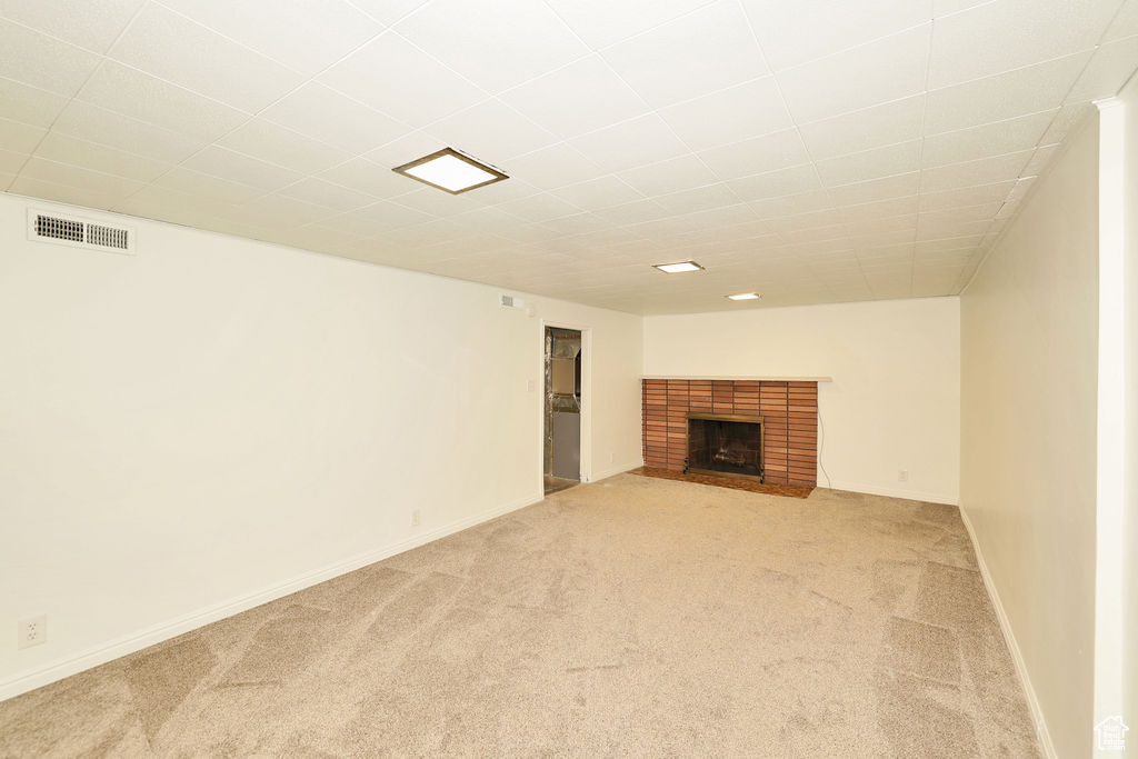Unfurnished living room with light colored carpet and a fireplace