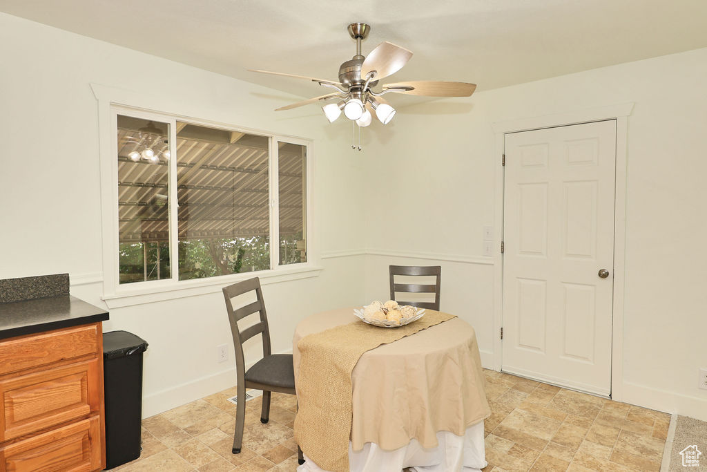 Dining area with ceiling fan and stone finish floors