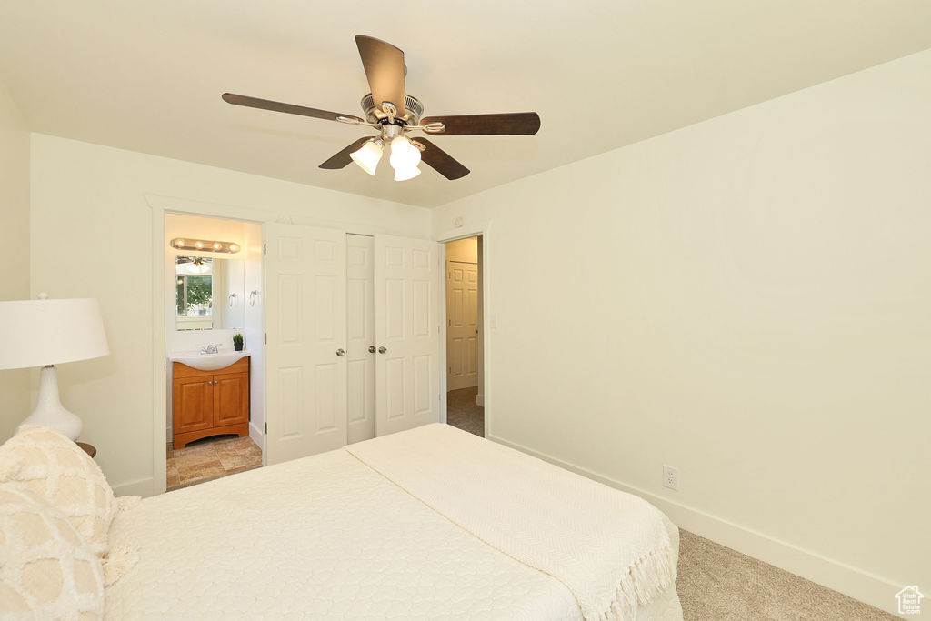 Carpeted bedroom with ensuite bath, a ceiling fan, and a closet