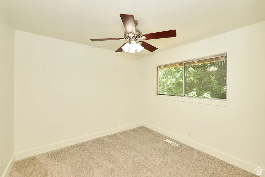 Empty room with light carpet and a ceiling fan