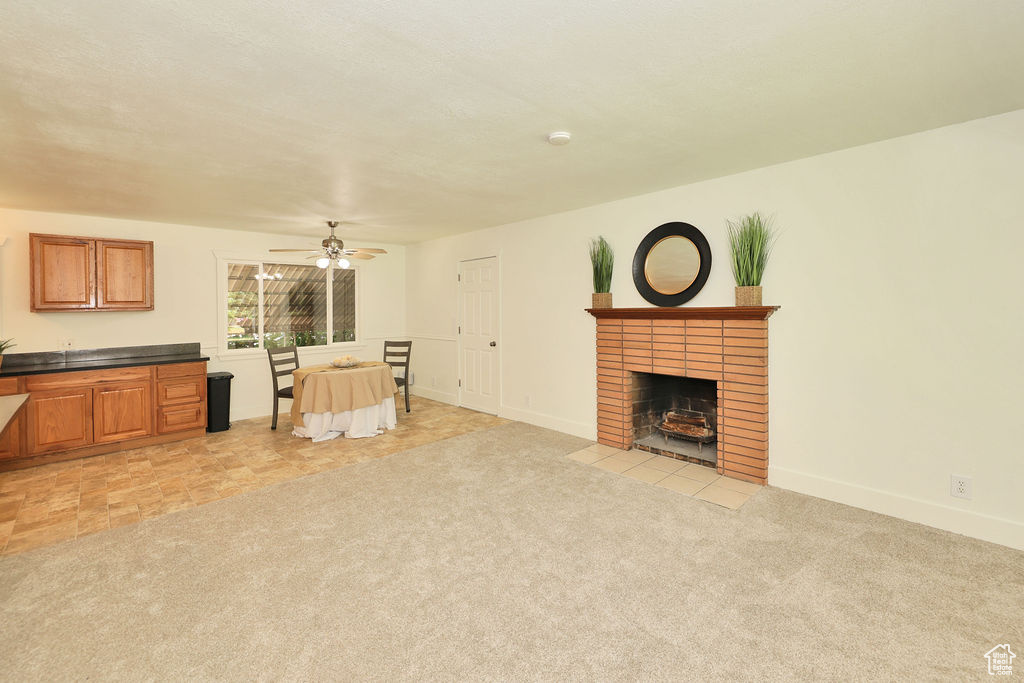 Living room featuring ceiling fan, light colored carpet, and a fireplace