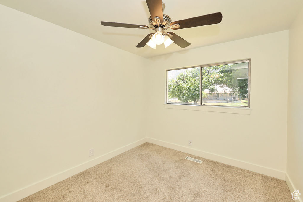Unfurnished room featuring light colored carpet and a ceiling fan