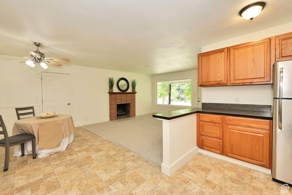 Kitchen with freestanding refrigerator, open floor plan, a ceiling fan, a peninsula, and dark countertops