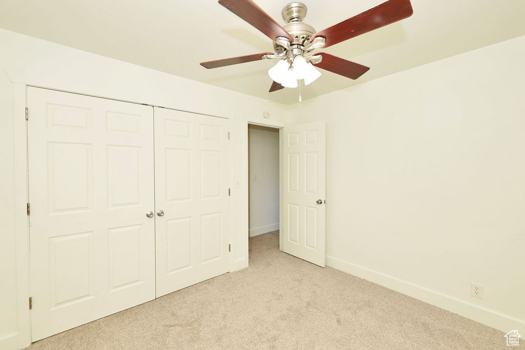 Unfurnished bedroom with light colored carpet, a closet, and ceiling fan