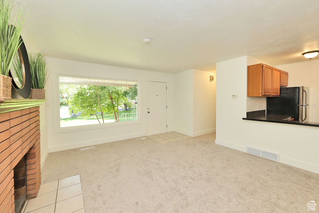 Unfurnished living room with a brick fireplace and light carpet
