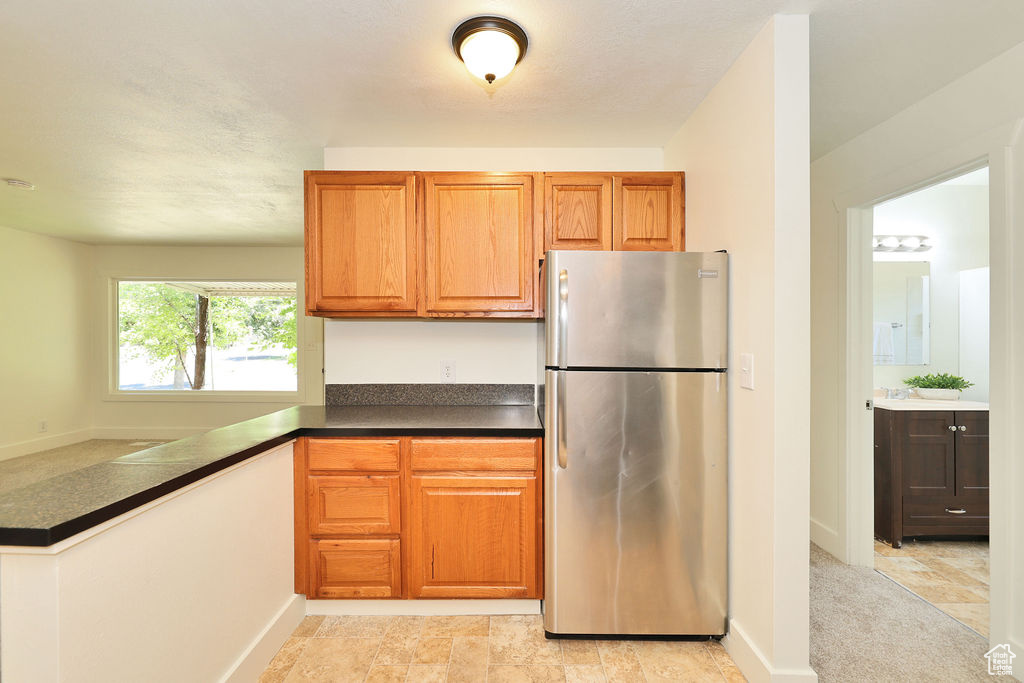 Kitchen featuring freestanding refrigerator, dark countertops, and brown cabinets