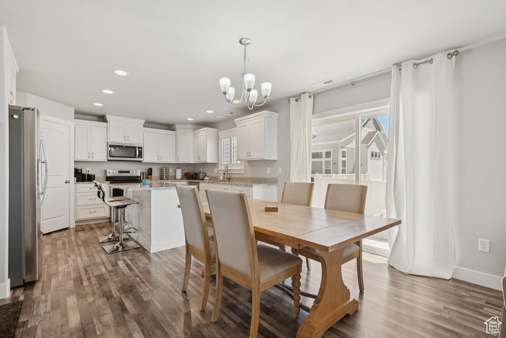 Dining area featuring a chandelier, wood finished floors, and recessed lighting