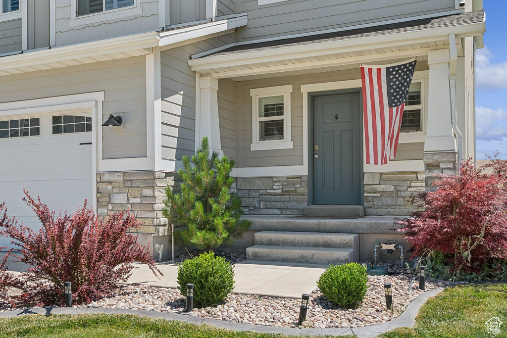 Entrance to property featuring stone siding and a porch