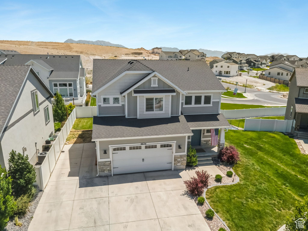 View of front of property with a garage, a residential view, stone siding, driveway, and a porch