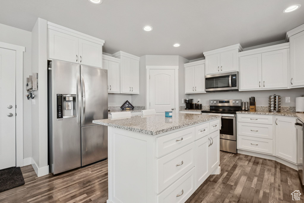 Kitchen featuring stainless steel appliances, dark wood finished floors, a kitchen island, recessed lighting, and white cabinets