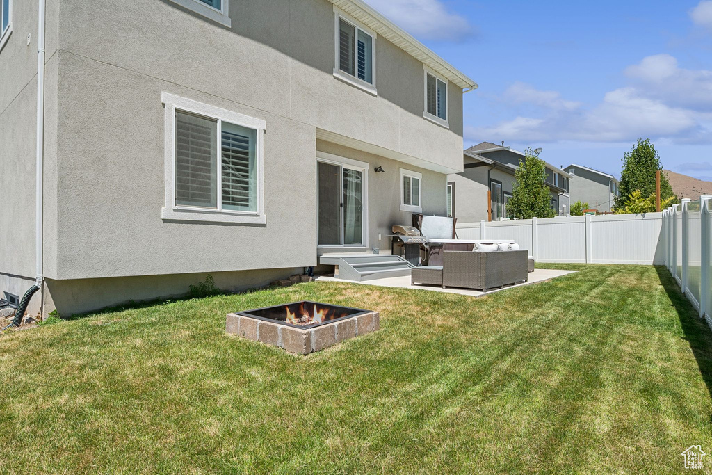Back of property with an outdoor living space with a fire pit, a fenced backyard, stucco siding, a patio, and a residential view