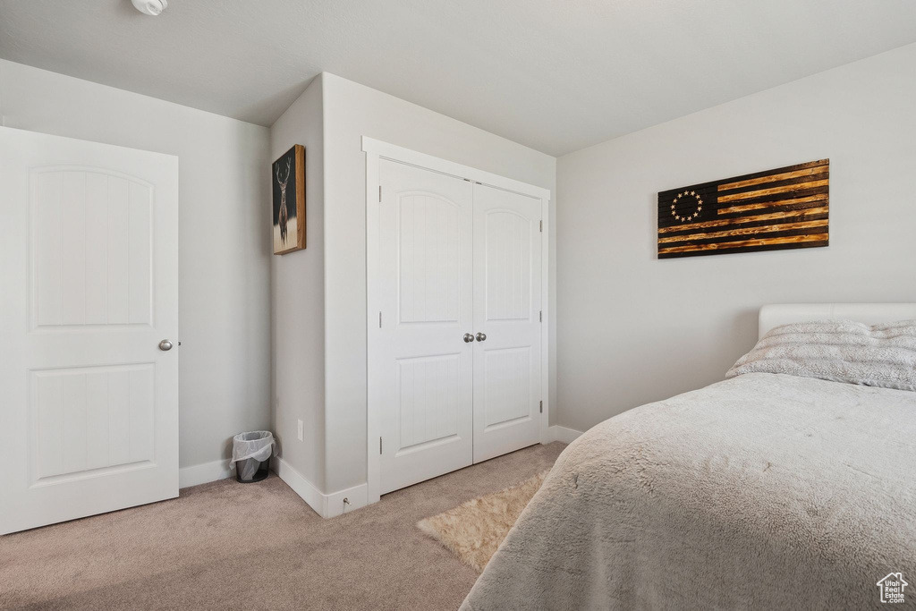 Carpeted bedroom featuring baseboards and a closet