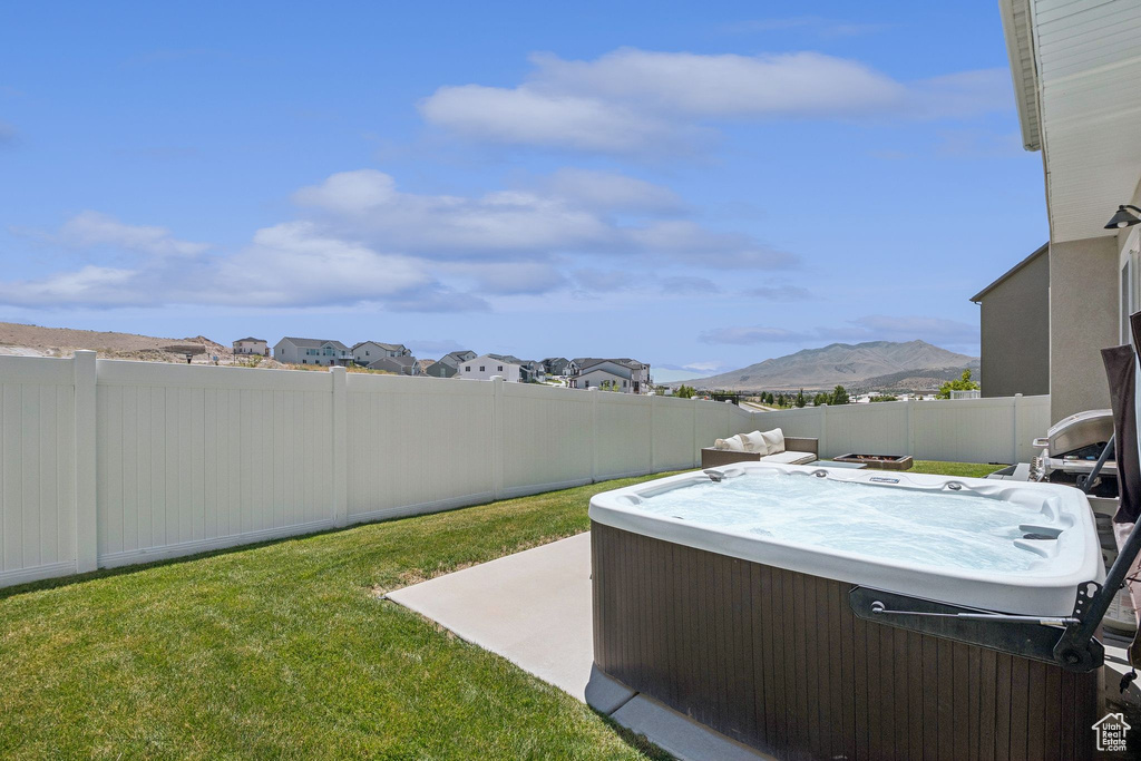 Fenced backyard with a hot tub, a mountain view, a patio, and a residential view