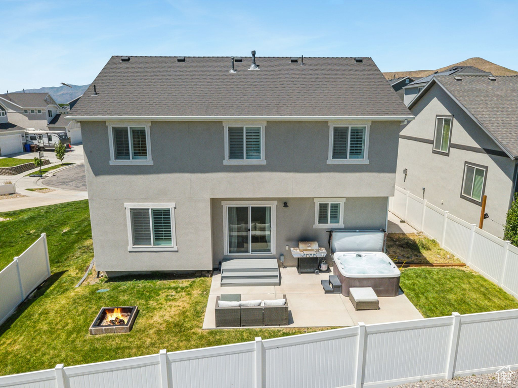 Back of house with a hot tub, an outdoor living space with a fire pit, a fenced backyard, and a patio area