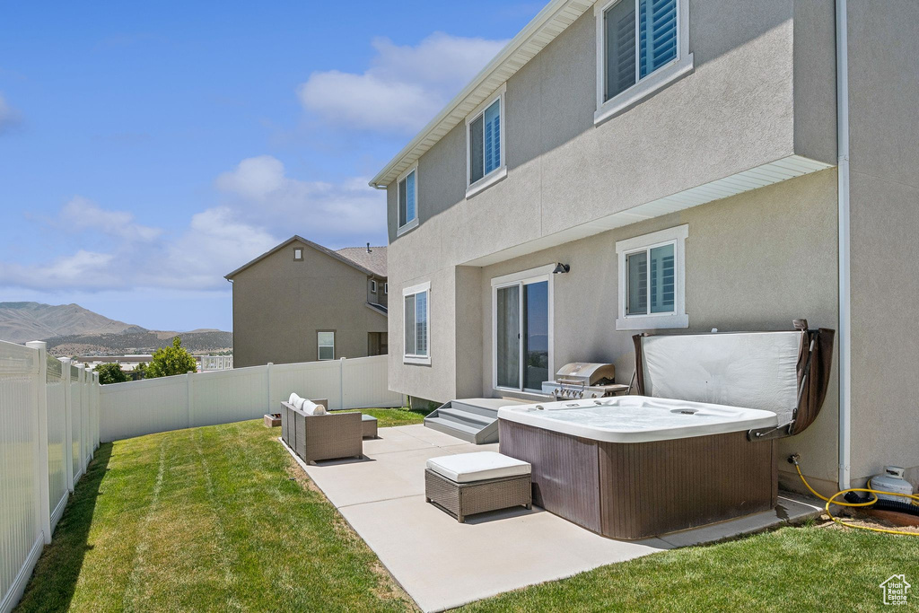 Back of house with a fenced backyard, a patio area, a mountain view, a hot tub, and outdoor lounge area