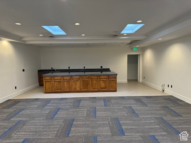Kitchen with a skylight, light carpet, recessed lighting, and brown cabinetry