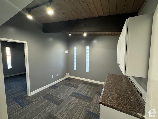 Spare room featuring dark carpet, a wood ceiling with exposed beams, and rail lighting