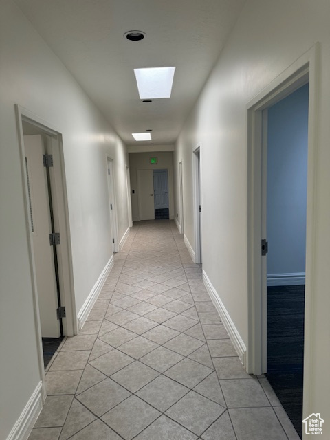 Hall with light tile patterned flooring and a skylight