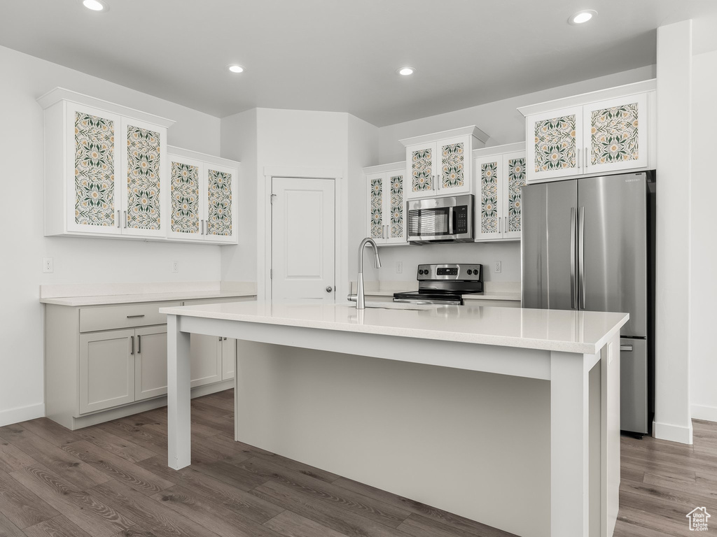 Kitchen with appliances with stainless steel finishes, light countertops, dark wood-style floors, recessed lighting, and glass insert cabinets