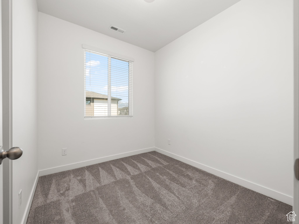 Empty room with dark colored carpet and baseboards