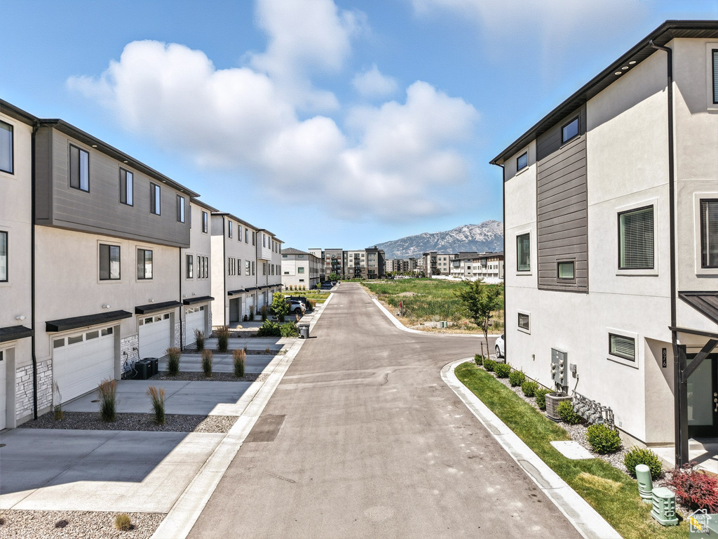 View of concrete street featuring a mountain view, curbs, and a residential view