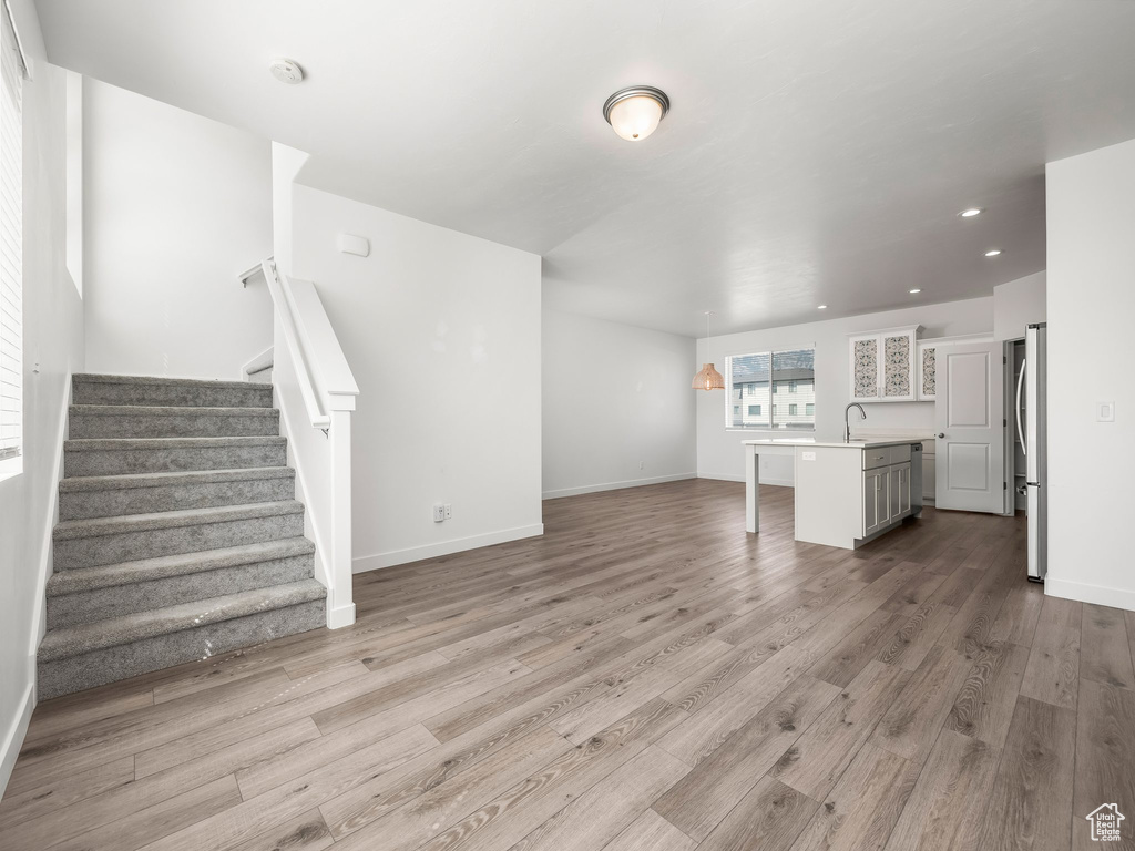 Unfurnished living room with stairs, wood finished floors, and recessed lighting